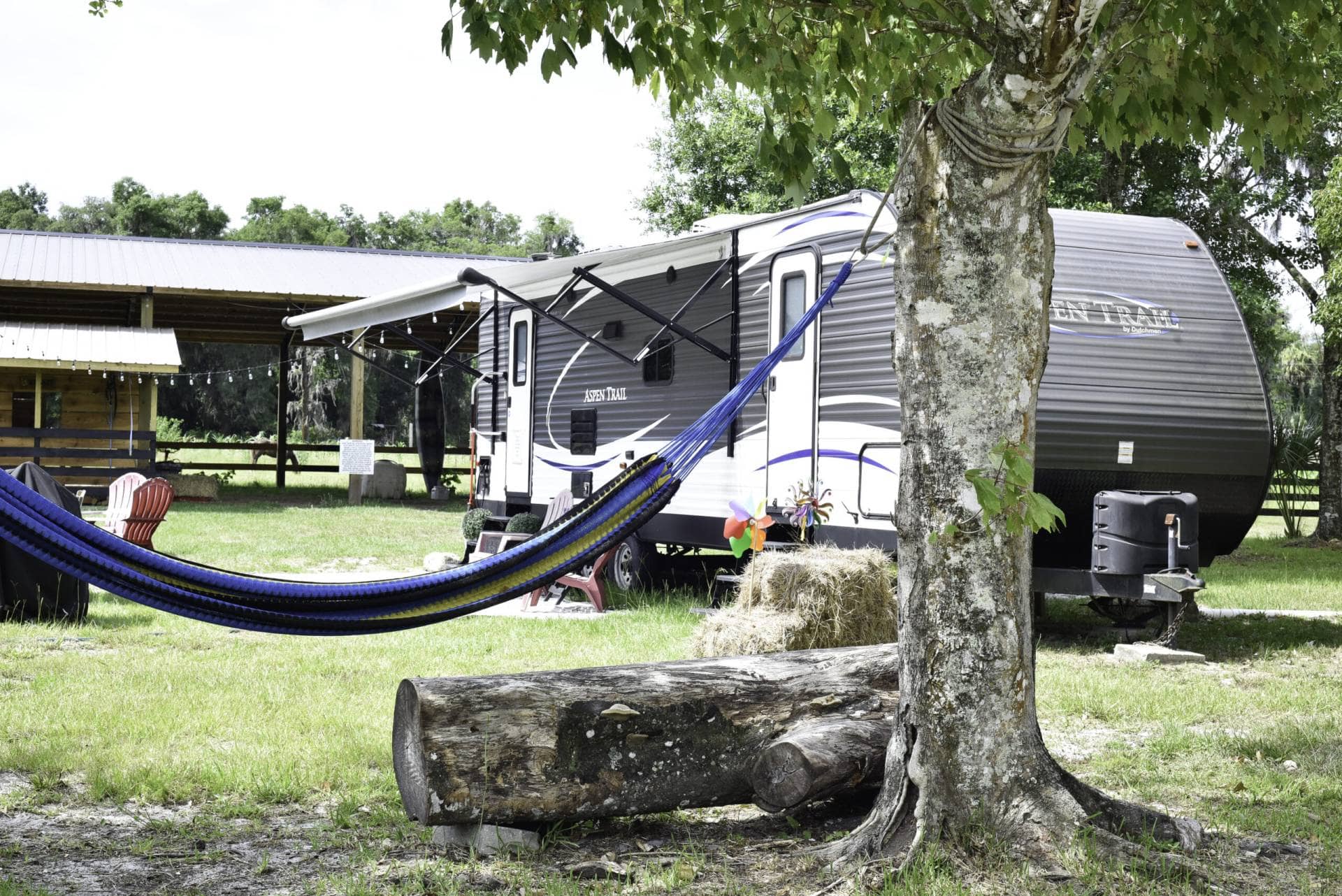 Relaxing area outside an Aspen Trail trailer with hammocks and seating at Golden Creek Ranch in Florida.